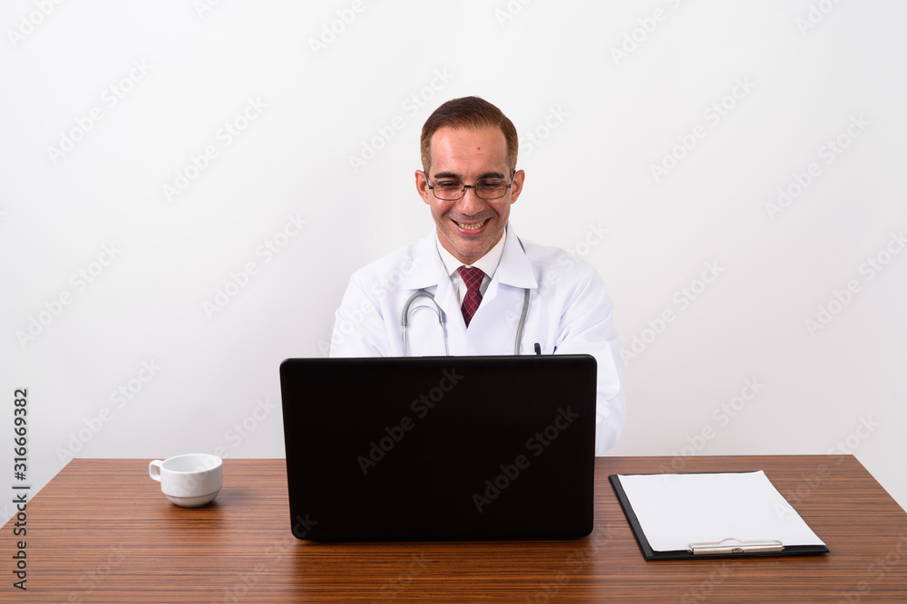 Mature Persian man doctor working behind desk