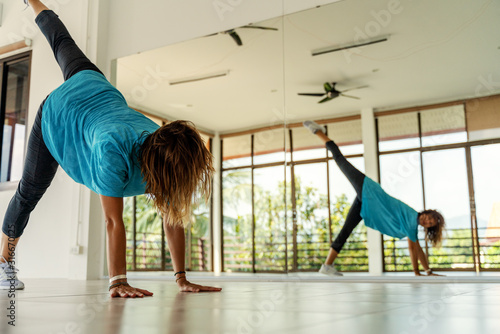 One European young woman dancing modern choreography in a fitness room in front of a mirror