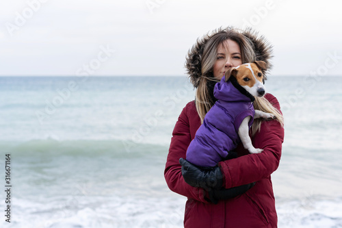Love for pets. Jack russell terrier dog in the arms of the mistress on the background of the sea landscape. Dog travel