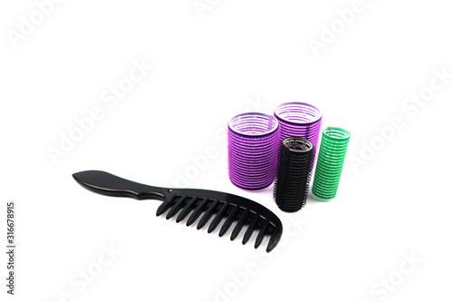 Black comb and hair curlers which are big and small size, color purple, black and green isolated on white background.
