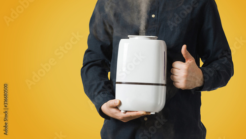Working humidifier with steam in men's hands. Thumbs up symbol.