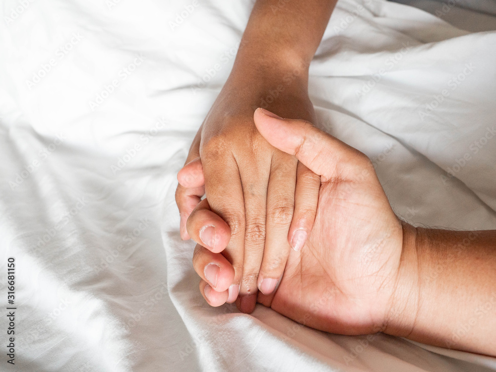 Holding hands man and woman on Bed White color Holding hands man and woman on Bed White color