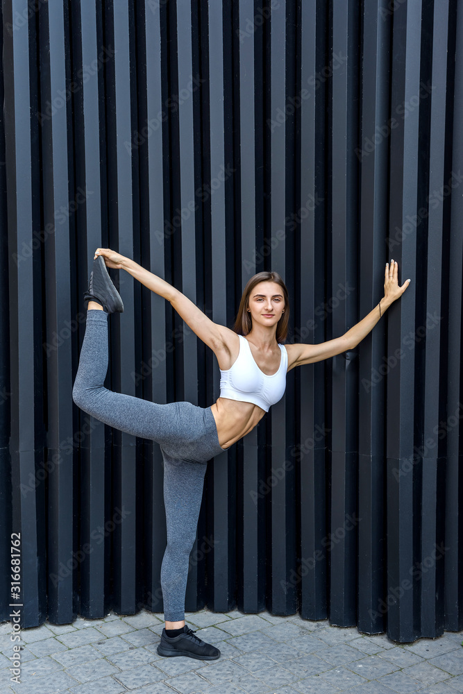 Sportive woman in city. Young girl making strength exercises on city streets Sportive woman in city. Young girl making strength exercises on city streets