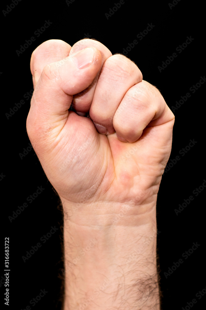male hand clenched into a fist on the black background male hand clenched into a fist on the black background