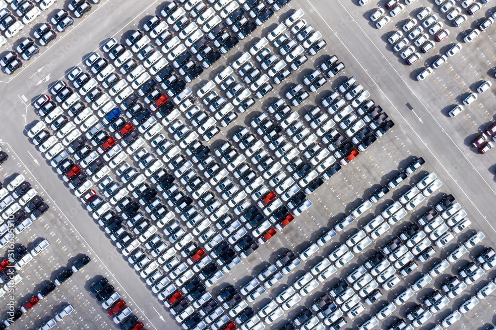 Aerial top view new cars lined up in the port for import export business logistic and transportation by ship in the open sea. New car from the factory parked at the port Aerial top view new cars lined up in the port for import export business logistic and transportation by ship in the open sea. New car from the factory parked at the port