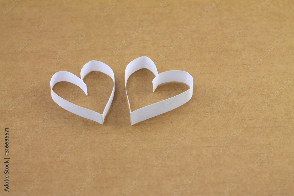 A pair of white hearts on a beige cardboard background with an empty place for your text. Valentine's day stock photo for web, print, postcards, invitations, wallpaper and 