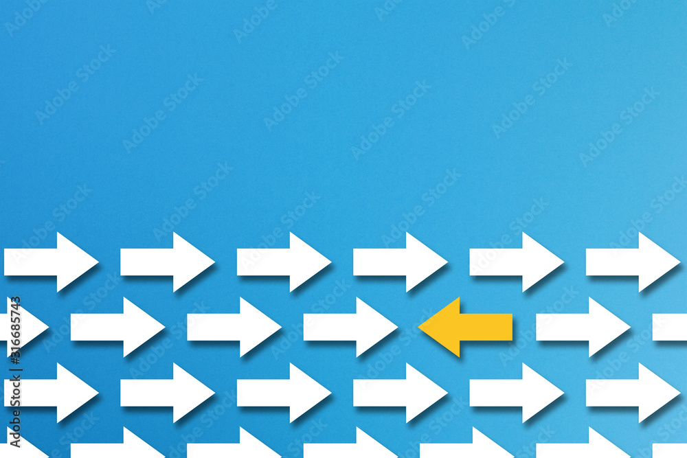 Yellow arrow goes in a different direction from the white arrows on blue background, different business concept