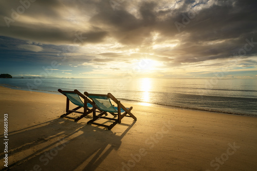 Two Beach Chairs standing in beach with beautiful sea and sunlight in background at island in Phuket, Thailand. Summer, Travel, Vacation and Holiday concept.