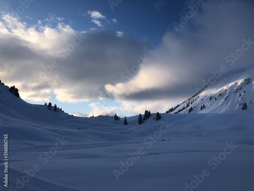 Wolkenreicher Himmel mit blauen Stellen über Schnee auf im Salober Gebiet.