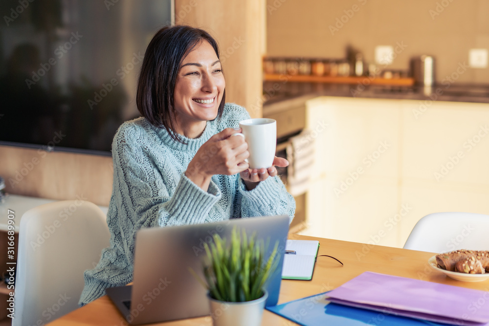 Smiling woman with laptop at home office Smiling woman with laptop at home office