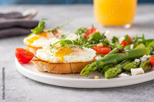 Egg and green asparagus on toast with greens. Healthy breakfast.