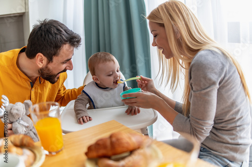 Parents feeding baby son at home