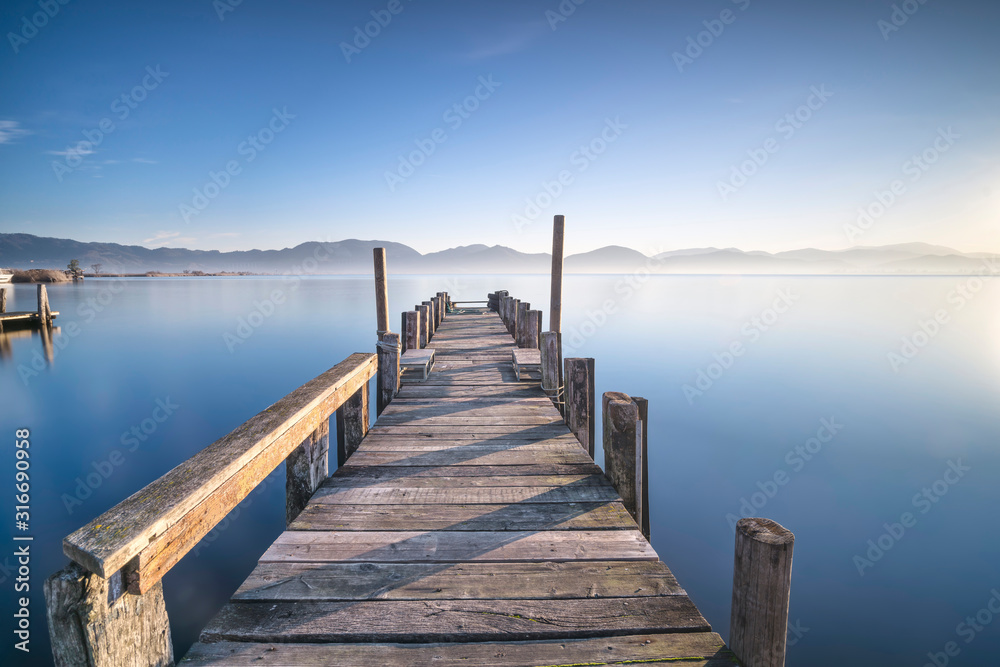 Wooden pier or jetty and lake at sunrise. Torre del lago Puccini Versilia Tuscany, Italy