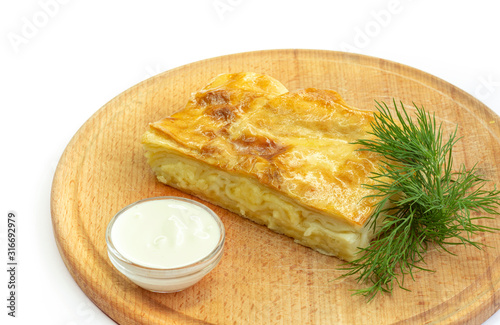 This is baked pastry in layers with feta cheese on a wooden board. photo