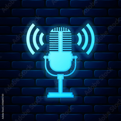 Glowing neon Microphone icon isolated on brick wall background. On air radio mic microphone. Speaker sign. Vector Illustration
