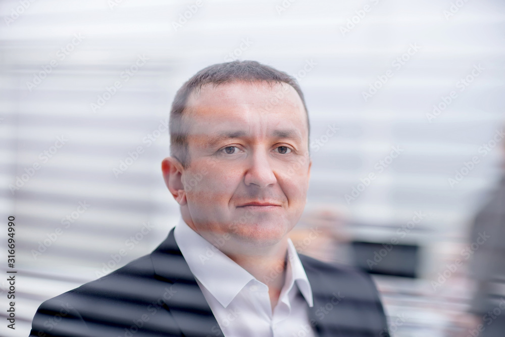 close up. confident business man looking through office window close up. confident business man looking through office window