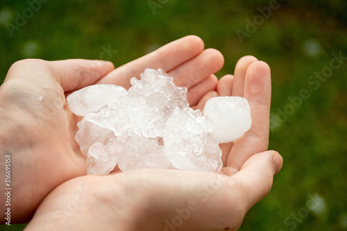 Hands holding large hailstones after severe hailstorm in Sydney, Australia