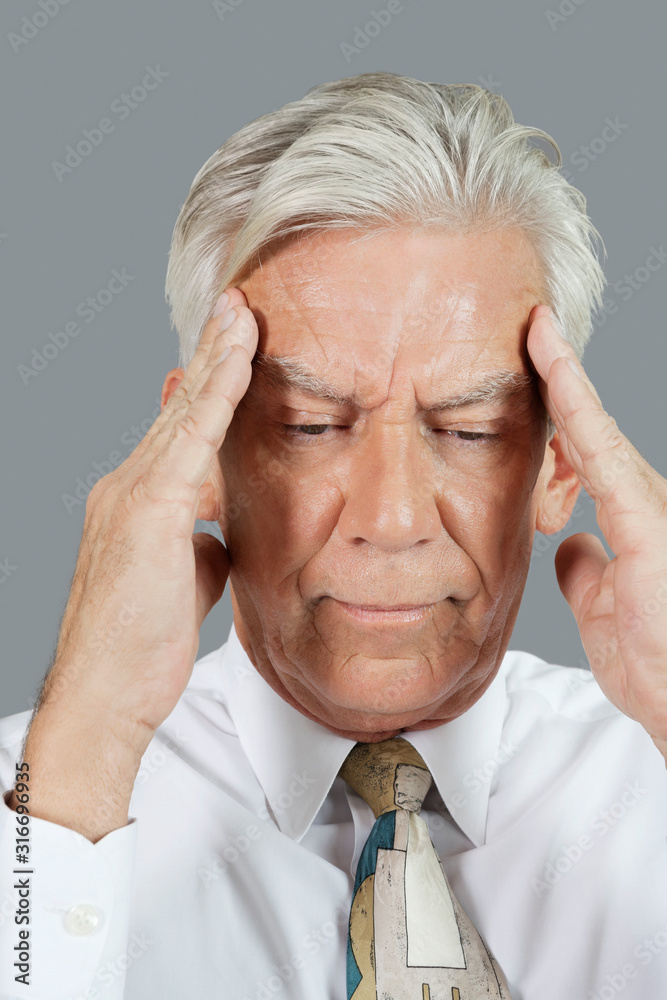 Close-up of senior businessman with headache over gray background Close-up of senior businessman with headache over gray background
