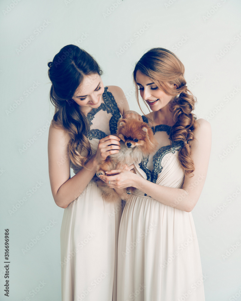 two cute girls are holding a cute little Spitz
