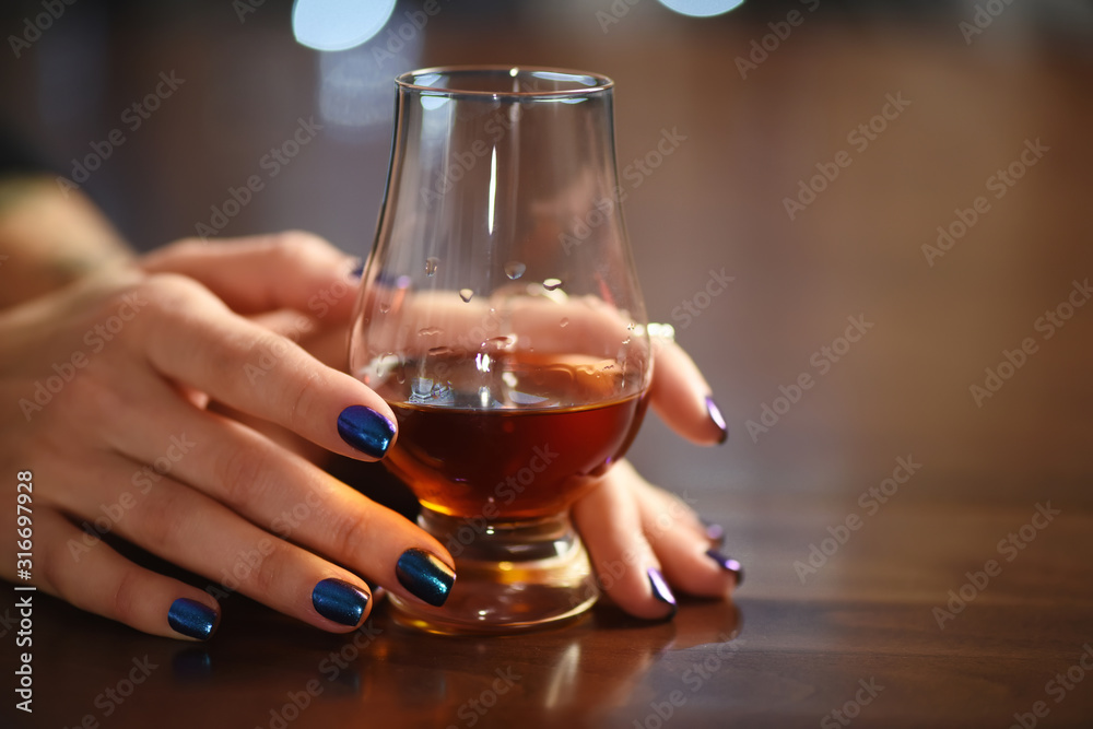 Woman hand holds a glass of whisky Woman hand holds a glass of whisky