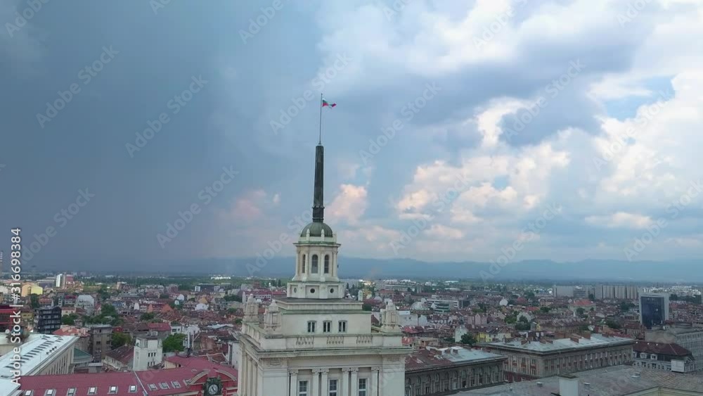 Ascending reveal drone shot of Bulgarian flag on top of a building in capital city