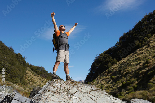Hiker with arms outstretched on rock in river