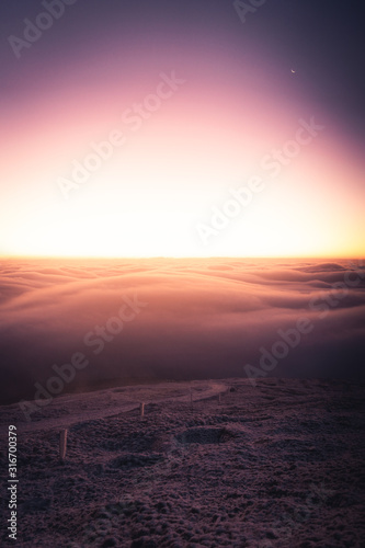 Winter landscape in Krkonose, beautiful sunrise with moon above the heavy clouds, shot from highest mountain in Czech republic called Snezka.