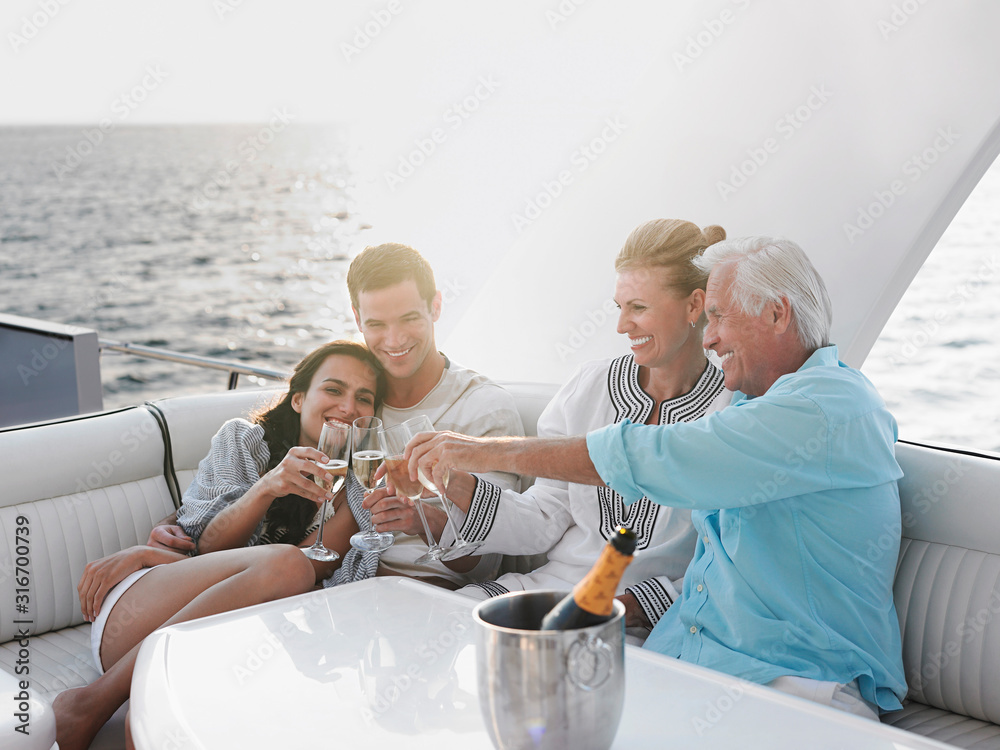 Two generational family celebrating with champagne on yacht - obrazy, fototapety, plakaty 