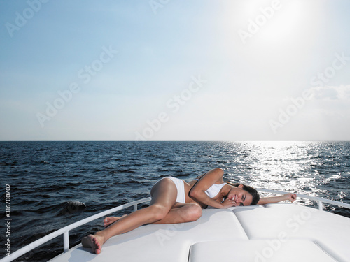 Young woman in bikini relaxing on yacht