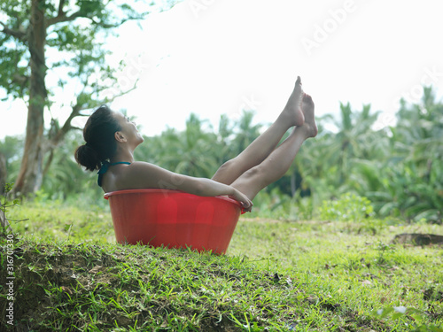 Young woman sitting in bowl outdoors side view