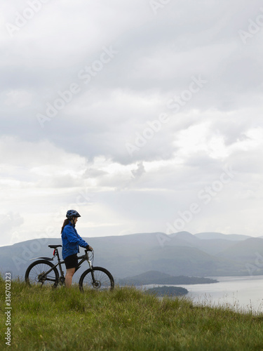 Cyclist in blue jacket looking out across the wilderness
