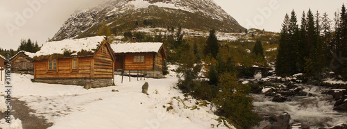 Holzhütten am Bach in winterlicher Gebirgslandschaft in Norwegen Panorama