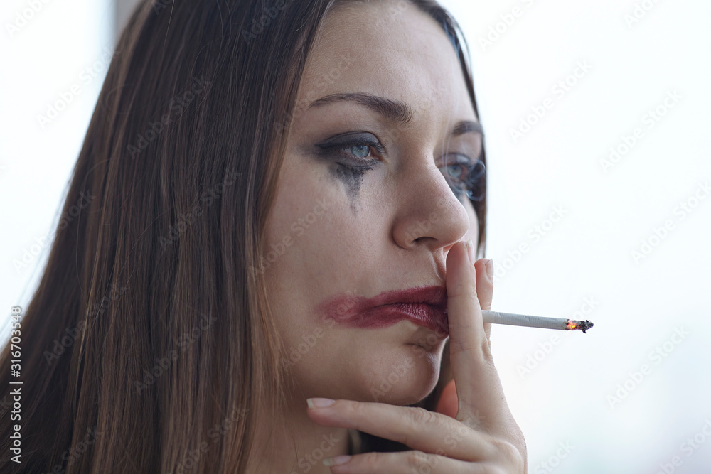 Young caucasian woman with greased sleazy make up smoking in stress or melancholy mood. Domestic violence concept, boozing, hangover. Сlose up portrait with all imperfections of real skin. Young caucasian woman with greased sleazy make up smoking in stress or melancholy mood. Domestic violence concept, boozing, hangover. Сlose up portrait with all imperfections of real skin.