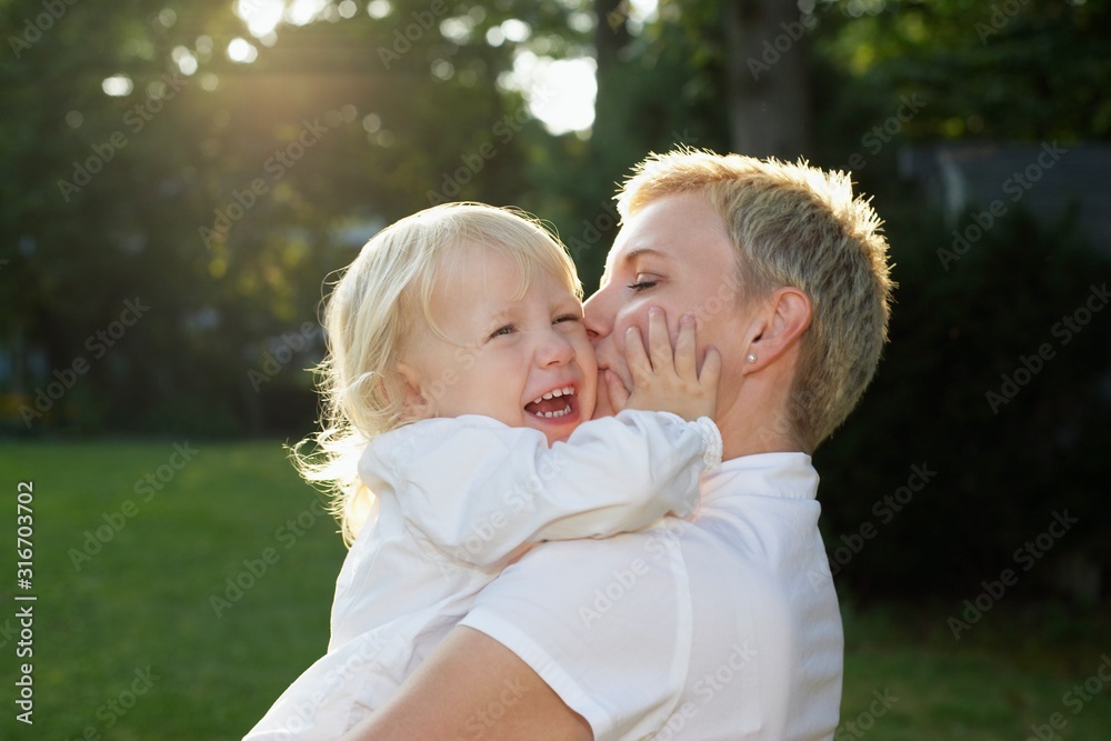 Mother carrying daughter (3-4) in garden girl crying Mother carrying daughter (3-4) in garden girl crying