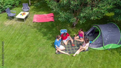 Family vacation in campsite aerial top view from above, parents and kids relax and have fun in park, tent and camping equipment under tree, family in camp outdoors concept 