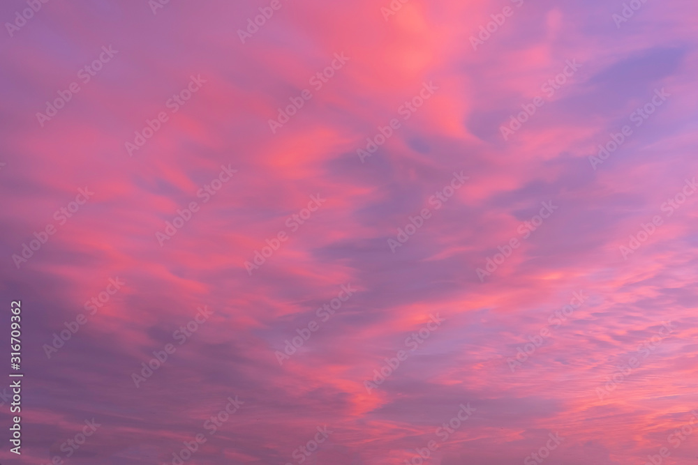 Pink orange sky during sunrise with scattered clouds