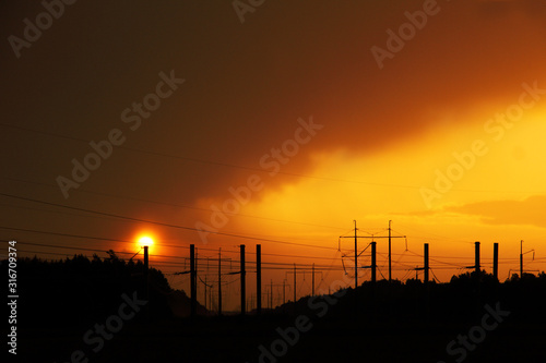 Silhouettes of wires of a high voltage power line against the backdrop of enchanting evening sunset. unusual urban landscape