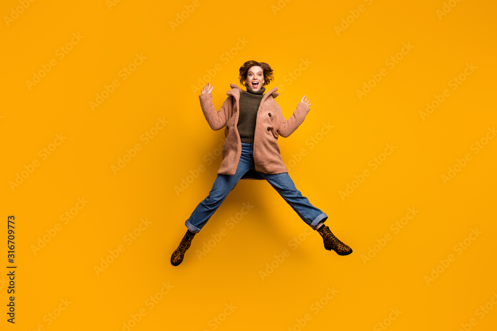 Full size photo of funky beautiful lady jump high up astonished vacation start rejoicing spread legs wear casual pink coat pullover jeans leopard shoes isolated yellow color background
