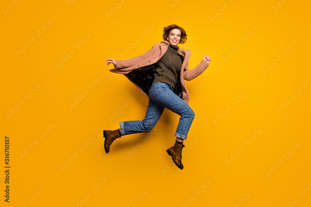 Full body profile photo of funny pretty lady jump high up rushing shopping center discounts wear casual pink coat pullover jeans leopard shoes isolated yellow color background
