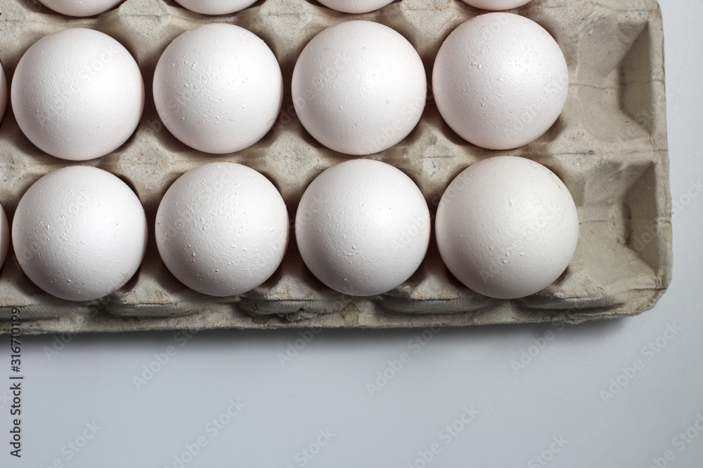 An isolated tray of eggs from recycled materials with white eggs on a white background. Top view An isolated tray of eggs from recycled materials with white eggs on a white background. Top view
