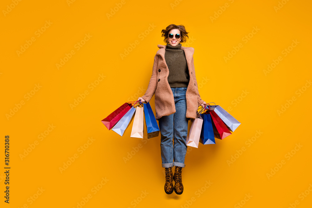 Φωτογραφία Full body photo of pretty funny lady jumping high up shopping center hold packs
