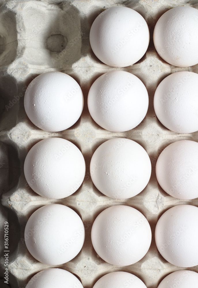 An isolated tray of eggs from recycled materials with white eggs on a white background. Top view An isolated tray of eggs from recycled materials with white eggs on a white background. Top view