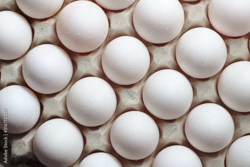 An isolated tray of eggs from recycled materials with white eggs on a white background. Top view An isolated tray of eggs from recycled materials with white eggs on a white background. Top view