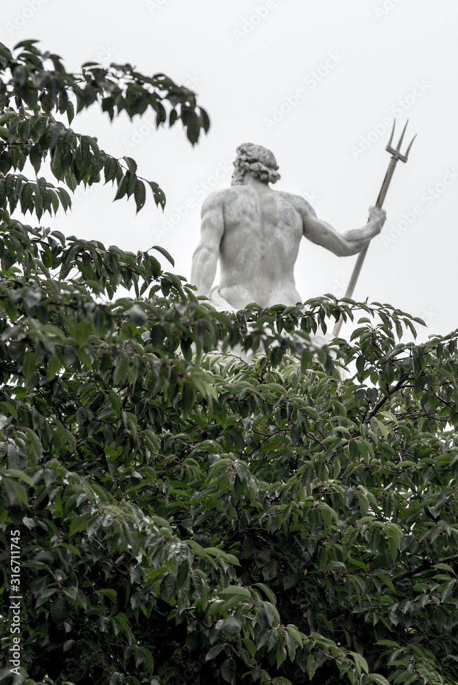 An abstract image with a statue of Neptune standing over the trees