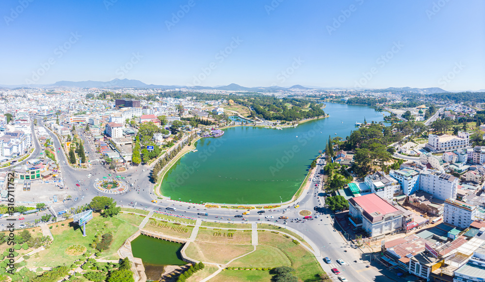 Aerial view of Da Lat city beautiful tourism destination in central highlands Vietnam. Clear blue sky. Urban development texture, green parks and city lake.