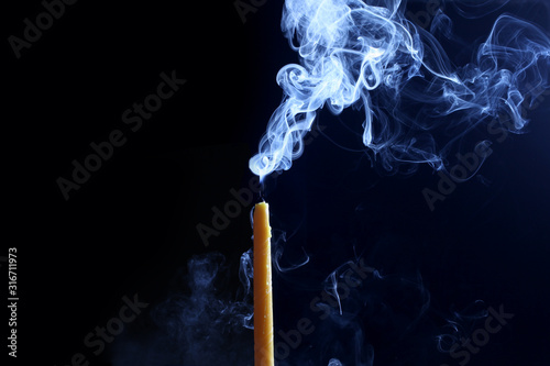 close up on a candle with smoke isolated on black background with copy space for your text