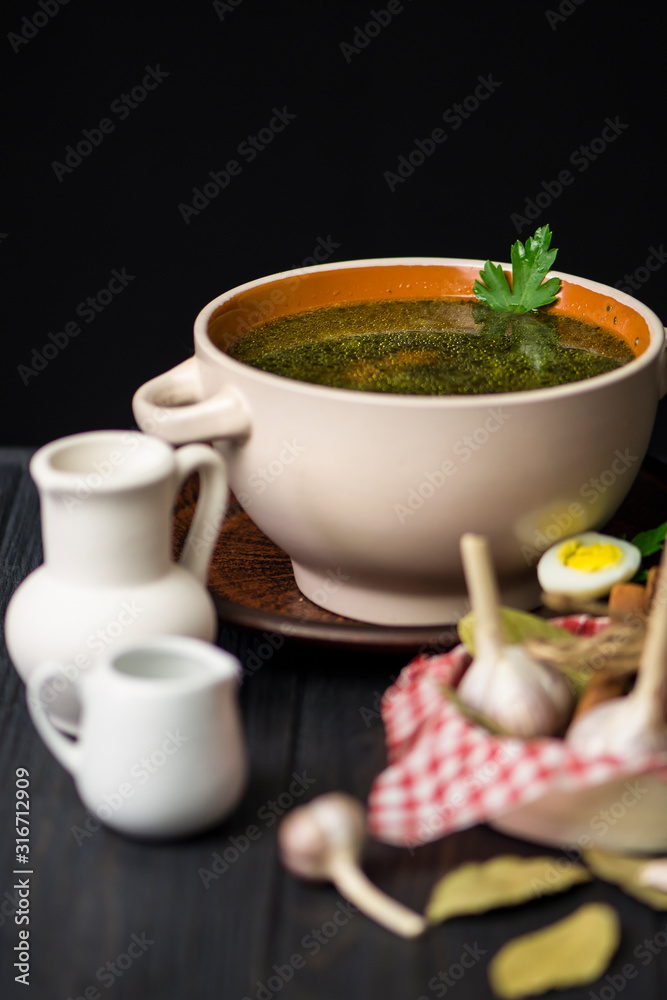 green soup, chicken broth with spinach on a dark wooden background green soup, chicken broth with spinach on a dark wooden background
