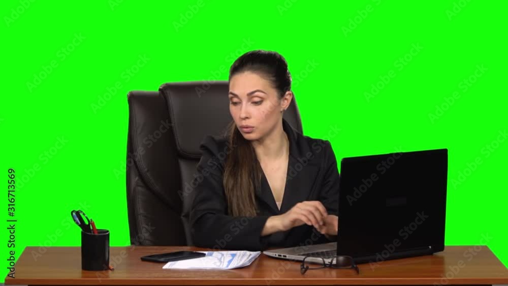 Woman working on a laptop then answers the call by mobile phonen, suprised and very happy when looks at documents. Green screen. Slow motion Woman working on a laptop then answers the call by mobile phonen, suprised and very happy when looks at documents. Green screen. Slow motion