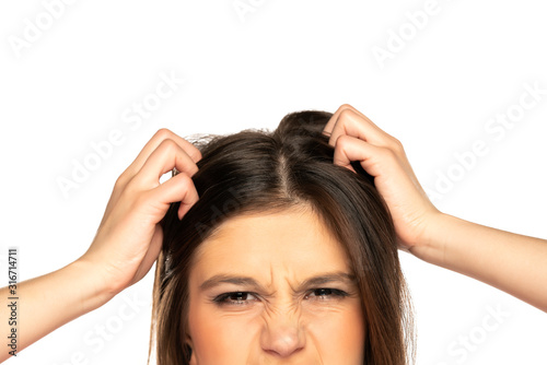 Half portrait of young nervous woman scratches her head