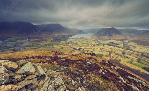 A hiker walking down from the mountain summit of Bield with views of Loweswater and Crmmock Water in the distance. photo